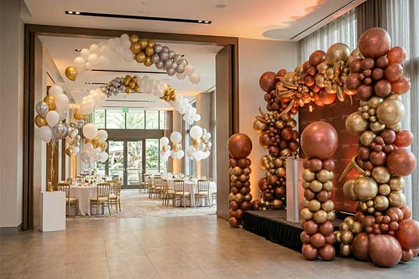 A beautiful event space featuring a strategic mix of floating helium centerpieces and a structured, air-filled balloon installation.
